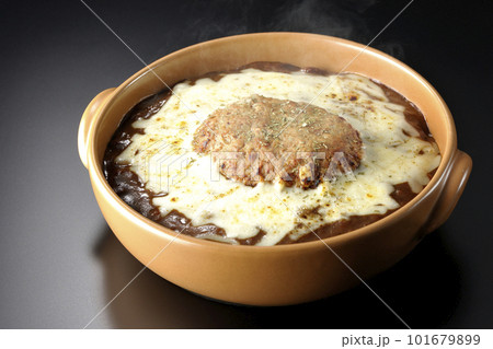 たっぷりのチーズとハンバーグが乗っている熱々焼きカレーを黒背景で撮影 101679899