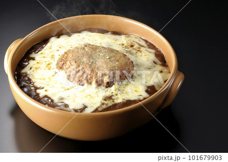 たっぷりのチーズとハンバーグが乗っている熱々焼きカレーを黒背景で撮影 101679903