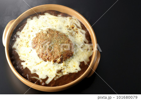 たっぷりのチーズとハンバーグが乗っている熱々焼きカレーを黒背景で俯瞰撮影 たっぷりのチーズとハンバーグが乗っている熱々焼きカレーを黒背景で俯瞰撮影 101680079