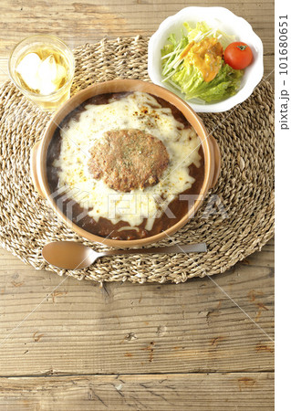 たっぷりのチーズとハンバーグが乗っている熱々焼きカレーとサラダ たっぷりのチーズとハンバーグが乗っている熱々焼きカレーとサラダ 101680651