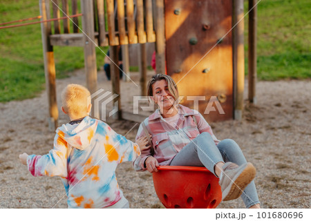 Mother and son having fun on a swing. Motherhood and childhood concept. Sunny summer day. Beautiful family is having fun outside. Parents with children riding on a swing. Mom is playing with her Mother and son having fun on a swing. Motherhood and childhood concept. Sunny summer day. Beautiful family is having fun outside. Parents with children riding on a swing. Mom is playing with her 101680696