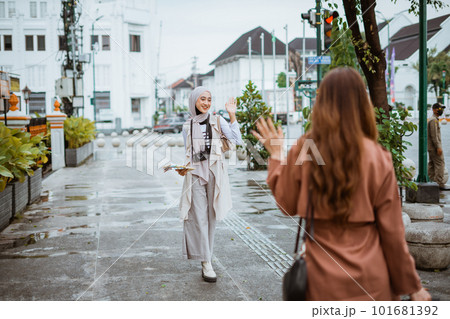female traveller with hijab waving her hand to her friend female traveller with hijab waving her hand to her friend 101681392