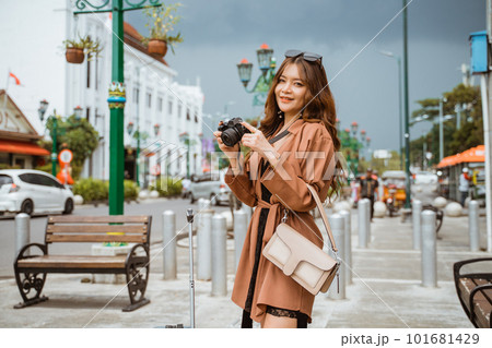 asian traveller in brown coat holding the camera asian traveller in brown coat holding the camera 101681429