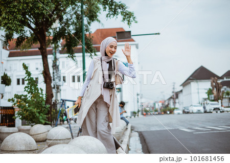 female traveller with hijab waving her hand female traveller with hijab waving her hand 101681456