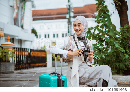 beautiful traveller with hijab smiling while holding the camera 101681468