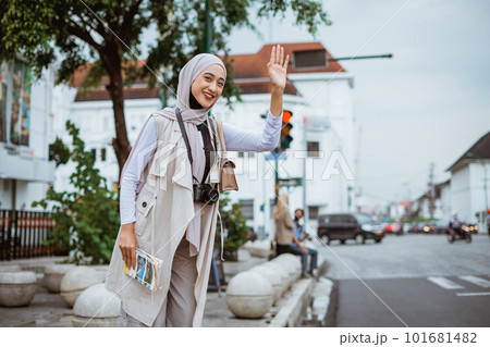 beautiful traveller with hijab smiling while trying to stopping the car beautiful traveller with hijab smiling while trying to stopping the car 101681482