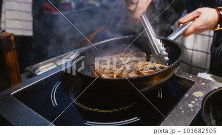 Male cook fries beef meat goulash on pan Male cook fries beef meat goulash on pan 101682505