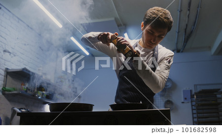 Male cook adds spices using spice grinder 101682598
