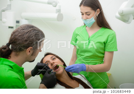 Woman sitting in dental chair at medical center while professional doctor fixing her teeth 101683449