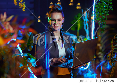 smiling stylish female using laptop in metaverse smiling stylish female using laptop in metaverse 101683520