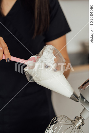 The girl cook puts the cream from the mixer into the mold for decorating cakes 101684060