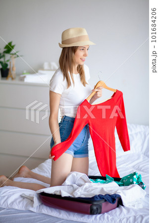 Beautiful young woman looking carefree and positive while packing her suitcase 101684206