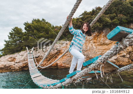 woman crossing suspension bridge sea on background 101684912
