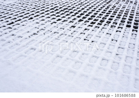 A checkered outline snowy pattern on dark cobblestones, perspective view on snow texture 101686588