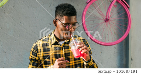 Banner carefree african american guy in casual wear holding tropical cocktail urban summer background copy space. Cool young man drinking yummy alcohol-free beverage on summer vacation 101687191