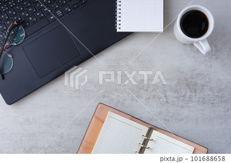 机にノートパソコンやノートを広げ、コーヒーを飲みながらデスクワークをしているイメージ 101688658