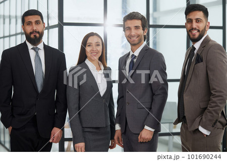 Businessmen with brunette in group posing in office lobby Businessmen with brunette in group posing in office lobby 101690244