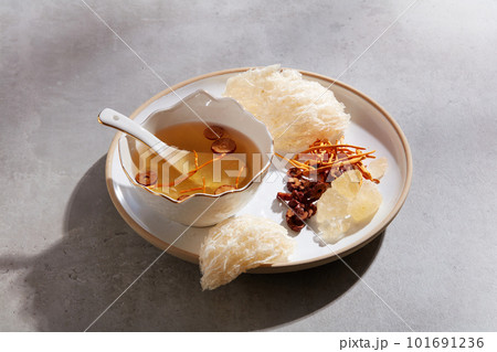 Edible bird nest displayed with a bowl of bird nest soup with jujube and cordyceps and rock sugar on a ceramic dish. A luxury combination for healthcare Edible bird nest displayed with a bowl of bird nest soup with jujube and cordyceps and rock sugar on a ceramic dish. A luxury combination for healthcare 101691236