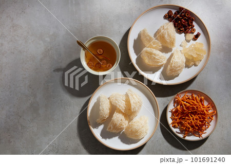 A dish of edible bird nest and jujube decorated with cordyceps and a ceramic bowl containing bird nest soup. Copy space. Healthcare concept 101691240
