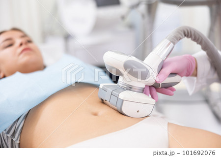 Unrecognizable masseur performing anti cellulite massage for belly of young woman in aesthetic medicine clinic 101692076
