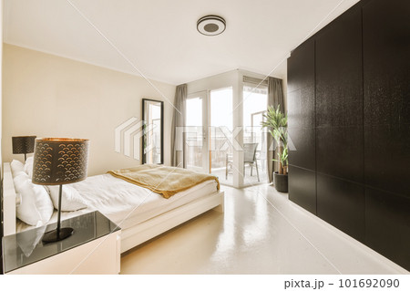 a bedroom with a large bed and black cabinetd cupboards on the wall next to the window in the room a bedroom with a large bed and black cabinetd cupboards on the wall next to the window in the room 101692090