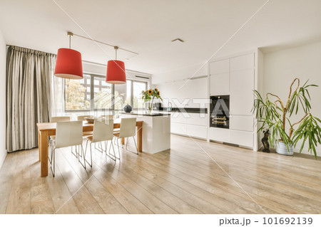 a dining room with wood flooring and white walls there is a red lamp on the table in front of the window a dining room with wood flooring and white walls there is a red lamp on the table in front of the window 101692139