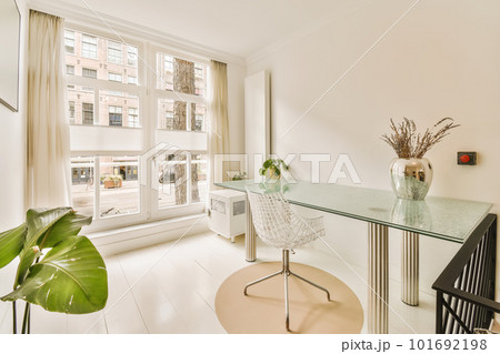 a room with a desk, chair and large window looking out onto the street in front of the apartment building a room with a desk, chair and large window looking out onto the street in front of the apartment building 101692198