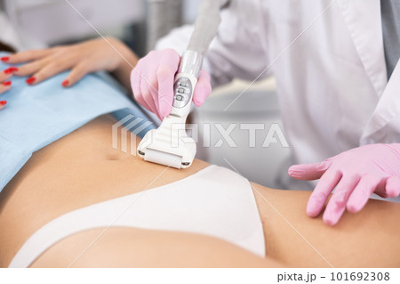 Unrecognizable masseur performing anti cellulite massage for belly of young woman in aesthetic medicine clinic 101692308