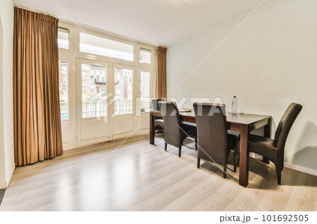 a dining table and chairs in a living room with sliding glass doors leading to the balcony area, which can be used as a 101692505
