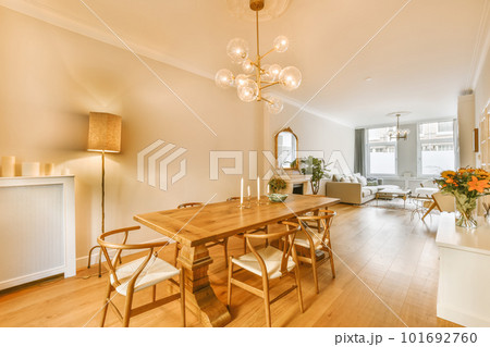 a dining room with wood flooring and white walls there is a chandel in the center of the room 101692760