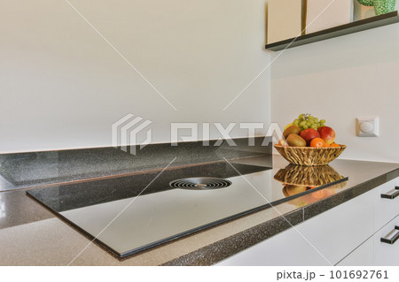 a bowl of fruit sitting on the kitchen counter in front of a sink that is white and has black granite 101692761