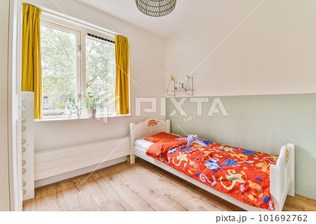 a child's room with yellow curtains on the window and white bed in the room is decorated with colorful toys 101692762