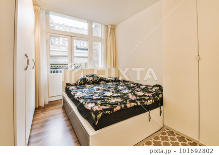 a bedroom with a bed and wardrobes in the corner, there is an open door leading to another room 101692802