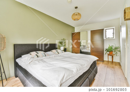 a bedroom with green walls and white bedding on the floor, there is a lamp in the corner above the bed 101692803