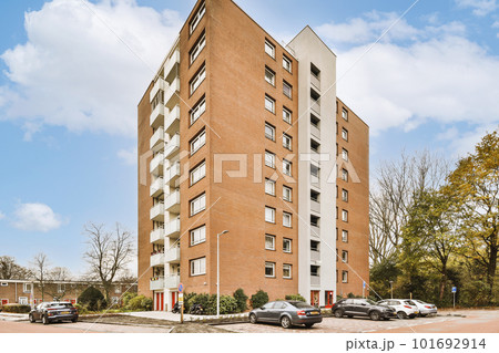 an apartment building with cars parked on the street next to it and trees in the fore - eyed area behind 101692914