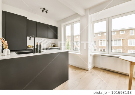 a modern kitchen with black cabinets and white countertops in the center of the image is an open window overlooking outside 101693138