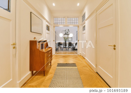 a long hallway with hardwood flooring and white trim on the walls, there is a small desk in the corner 101693189
