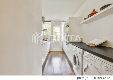 a laundry room with wood flooring and white washer in the area is well lit by natural light from the window 101693212