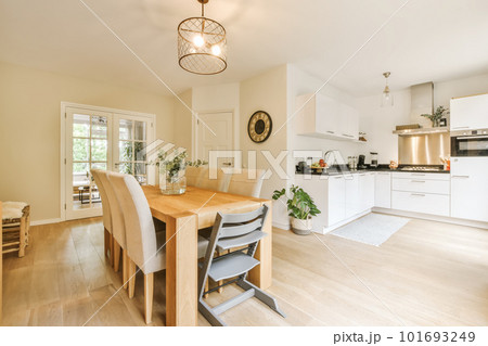 a kitchen and dining area in a house with white walls, hardwood flooring and light wood table surrounded by chairs a kitchen and dining area in a house with white walls, hardwood flooring and light wood table surrounded by chairs 101693249