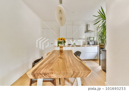 a kitchen and dining area in a house with white walls, hardwood flooring and an island table surrounded by wooden chairs a kitchen and dining area in a house with white walls, hardwood flooring and an island table surrounded by wooden chairs 101693253