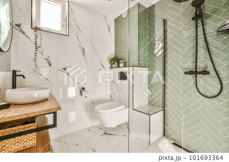 a modern bathroom with green tiles and white marble flooring on the walls, along with a wooden vanity sink 101693364