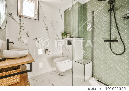 a modern bathroom with green tiles and white marble flooring on the walls, along with a wooden vanity sink 101693366