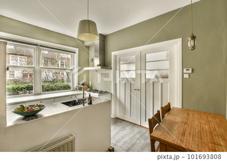 a kitchen and dining area in a house with green walls, white trim around the windows, and wood floors 101693808