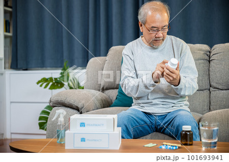 Asian worried senior man with medicine pills he read on see how to take pills before taking, old man buy herbal self cure Rx pill online from pharmacy, home isolation, Medical service concept 101693941