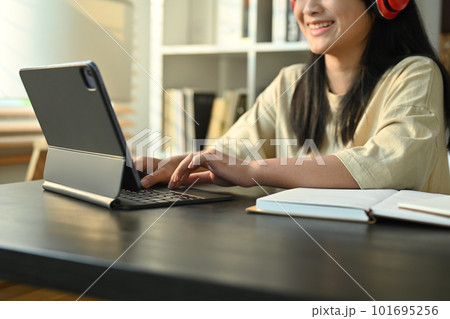 Smiling teenage girl in headphones studying online classes on digital tablet at home. Online learning concept Smiling teenage girl in headphones studying online classes on digital tablet at home. Online learning concept 101695256