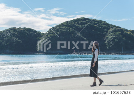 朝日で輝く秋の海の砂浜を歩く女性（静岡県 伊豆 弓ヶ浜） 101697628