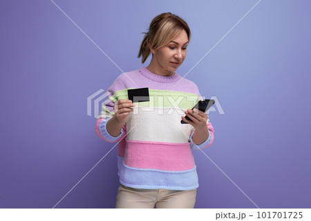 attractive blond young woman in pastel color sweater smiling holding credit card mockup on lilac attractive blond young woman in pastel color sweater smiling holding credit card mockup on lilac 101701725