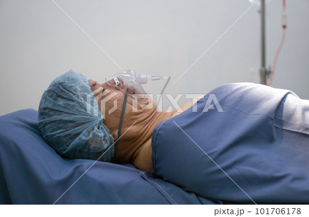 Asian senior patient breathing with respirator, lying on hospital bed in operating room waiting for operate surgery. Asian senior patient breathing with respirator, lying on hospital bed in operating room waiting for operate surgery. 101706178