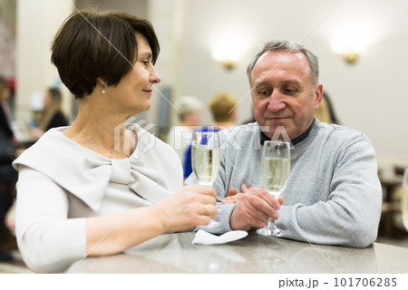 Mature man and woman drinking champagne in theater lobby 101706285