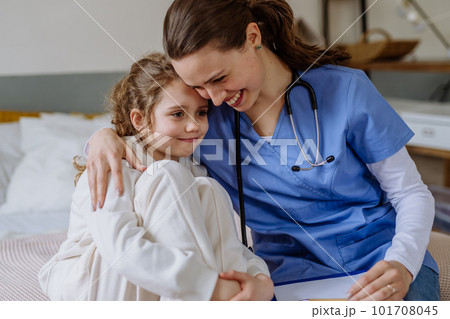 Young doctor hugging little girl in hospital room. 101708045
